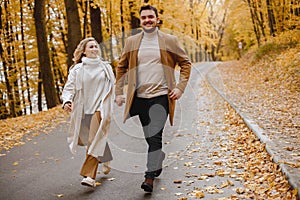 Romantic couple walking in autumn forest and holding hands