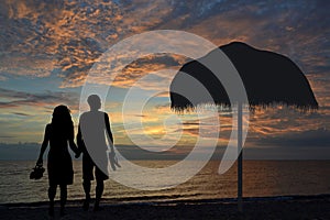 Romantic couple  walking on the beach holding hands together in the  sunset with slippers in hand