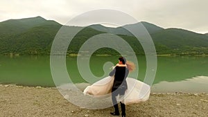 Romantic date bride and groom near the river on the background of picturesque mountains