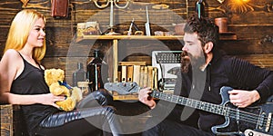 Romantic date concept. Couple spend romantic evening, wooden interior background. Man play guitar while lady holds teddy