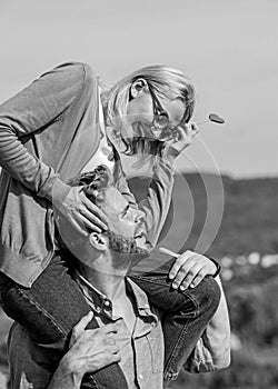 Romantic date concept. Man carries girlfriend on shoulders, sky background. Couple in love walking outdoor sunny day