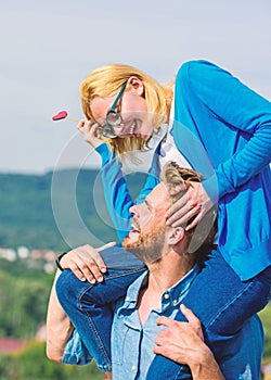 Romantic date concept. Man carries girlfriend on shoulders, sky background. Couple in love walking outdoor sunny day