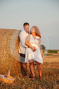 Romantic date on a freshly cut field near a haystack