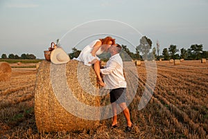 Romantic date on a freshly cut field near a haystack
