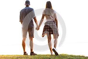 Young couple in love walking in the autumn park holding hands looking in the sunset