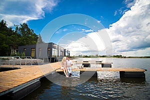 Romantic date surprise. A young guy and a girl on a wooden pier. Hug and kiss while sitting on the pier. Romantic love story