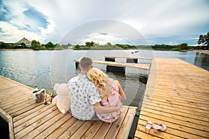 Romantic date surprise. A young guy and a girl on a wooden pier. Hug and kiss while sitting on the pier. Romantic love story