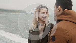 Romantic date of young loving couple on black beach, near the troll toes rocks in Iceland. Tourists spend time together.