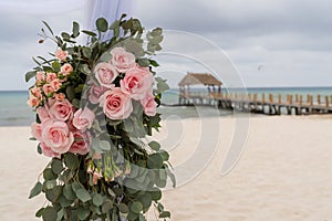Romantic decoration with pink roses of a beach wedding on the beach with sea in the background