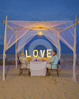 Romantic dinner on the beach in Phuket Thailand, couple man and woman having dinner on the beach