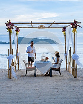 Romantic dinner on the beach in Phuket Thailand, couple man and woman mid age Asian woman and European man having a