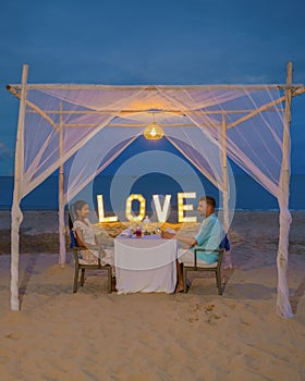 Romantic dinner on the beach in Phuket Thailand, couple man and woman having dinner on the beach