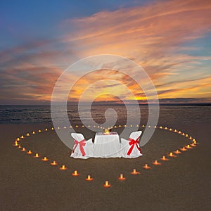 Romantic dinner with candles heart at sunset ocean beach. Proposal, wedding or honeymoon concept.