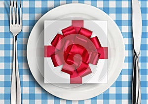 Romantic dinner concept, gift with ribbon on plate. Top view