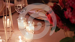 Romantic dinner at restaurant or at home. Table setting with candles and flowers