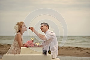 Romantic dinner by the sea. Wedding couple eating on beach