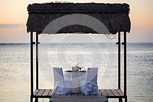 Romantic dinner setting on the beach at sunset.
