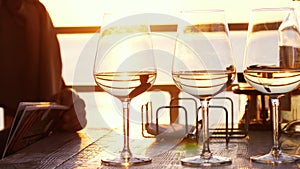 A romantic dinner in summer on a beach at sunset with three glasses of white wine and a bottle of the wine by the sea