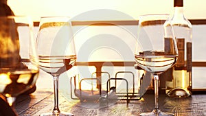 A romantic dinner in summer on a beach at sunset with two glasses of white wine and a bottle of the wine