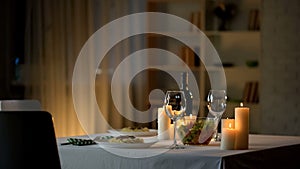 Romantic dinner table setting, wine glasses and fresh salad in bowl, home date