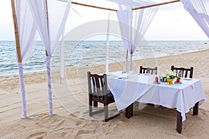 Romantic dinner table for three at a sandy beach in Thailand