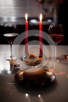Romantic dinner two glasses of wine and candels, hamburger, nuggets are in the dark with new year lights at the background