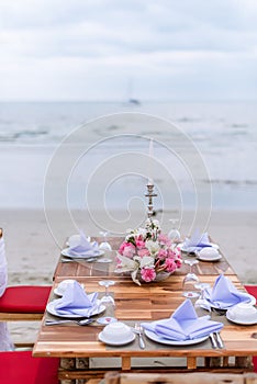 Romantic dinning table on the beach . Table setting at a luxury wedding and Beautiful flowers on the table.