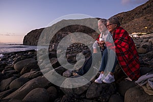 Romantic elderly aged senior people couple together in front of the ocean enjoying the sunset and the retired lifestyle -