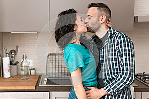 Romantic engaged couple is kissing in the kitchen of their new home - concept of romance and happiness in young couples