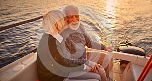 Romantic evening on the boat. Portrait of happy senior couple holding hands, hugging and kissing