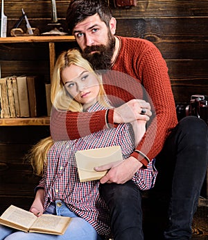 Romantic evening concept. Lady and man with beard on dreamy faces hugs and reading romantic poetry. Couple in wooden