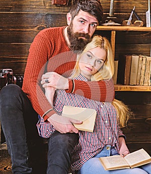 Romantic evening concept. Lady and man with beard on dreamy faces hugs and reading romantic poetry. Couple in wooden