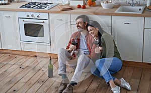 Romantic evening at home. Young happy romantic couple, wife and husband sitting on the floor in the modern kitchen