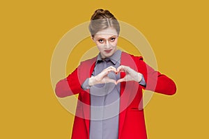 Romantic flirting woman showing heart shape with hands, looking at camera, expressing devotion.