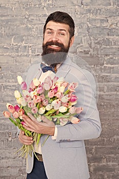 Romantic gift. Macho getting ready romantic date. Tulips for sweetheart. Man well groomed wear blue tuxedo bow tie hold