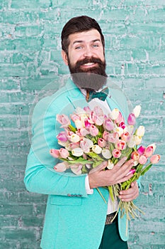 Romantic gift. Macho getting ready romantic date. Tulips for sweetheart. Man well groomed wear blue tuxedo bow tie hold