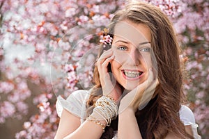 Romantic girl with braces near blossoming tree