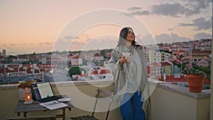 Romantic girl drinking coffee sunrise city view balcony. Lady looking distance