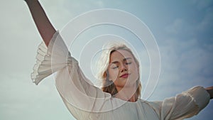 Romantic girl enjoy wind standing sunlight close up. Woman raising hands to sky.