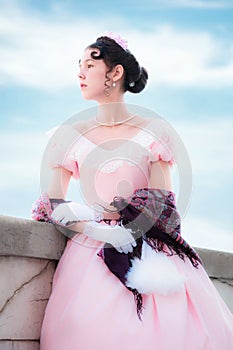 Romantic girl in evening dress is standing on the balcony.