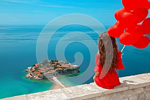 Romantic girl in red dress over Sveti Stefan island in Budva, Mo