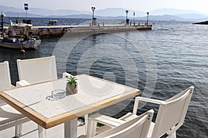 Romantic Greek restaurant with white chairs and tables near sea, tourism travel