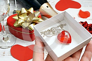 romantic greeting card with bottle of champagne, two glasse, and red pendant heart as gift