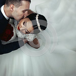 Romantic groom kissing brunette bride on the neck, shot from above closeup