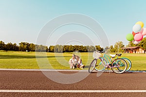 Romantic happy couple in love sitting on the grass at their bicycles