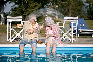 Romantic elderly couple  enjoy on summer holiday near swimming pool and  eating watermelon