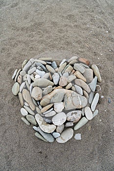 Romantic heart shape made from pebbles on a sandy beach, top view. Romance, valentine made from stones on black sand