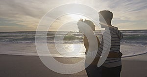 Romantic hispanic couple standing and embracing on beach at sunset