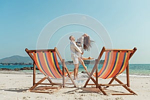 Romantic holiday travel. Portrait of happy young couple hugging near with deck chairs in luxury beach hotel at sunset