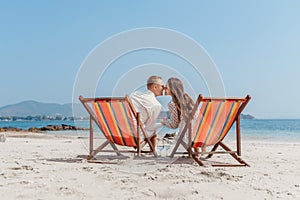 Romantic holiday travel. Portrait of happy young couple hugging near with deck chairs in luxury beach hotel at sunset